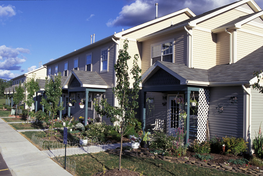 A row of houses with well kept gardens in front.